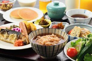 Variedad de platos, incluyendo panqueques, un tazón de arroz y una ensalada, sobre una mesa.