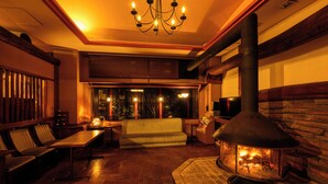 A cozy living room with a fireplace, wooden furniture, and a comfortable seating area. - Hotel Asyl Nara (Nara)