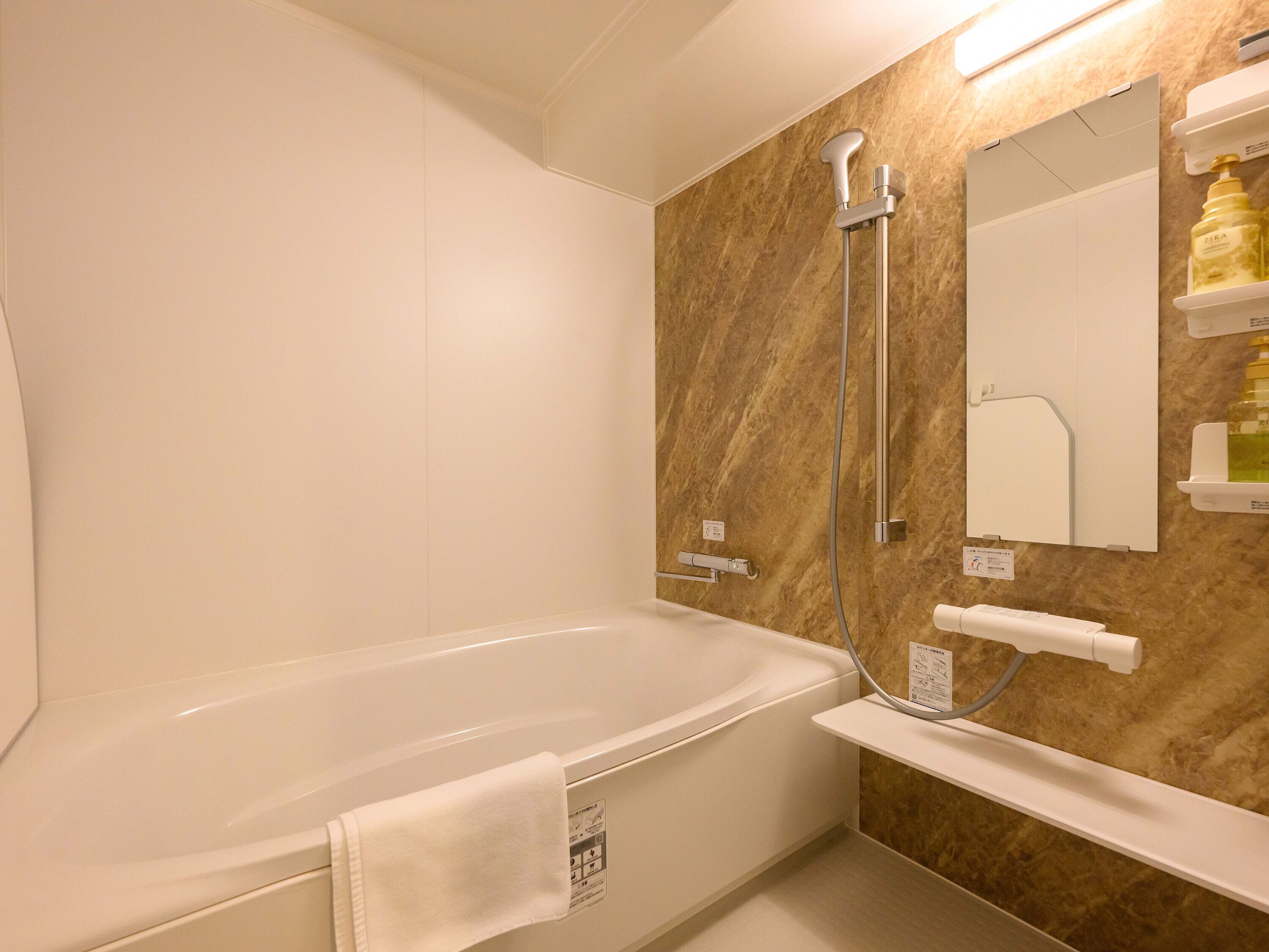 A modern bathroom with a freestanding bathtub, a showerhead, and a mirror.
