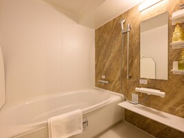 Un baño moderno con una bañera independiente, un cabezal de ducha y un espejo.