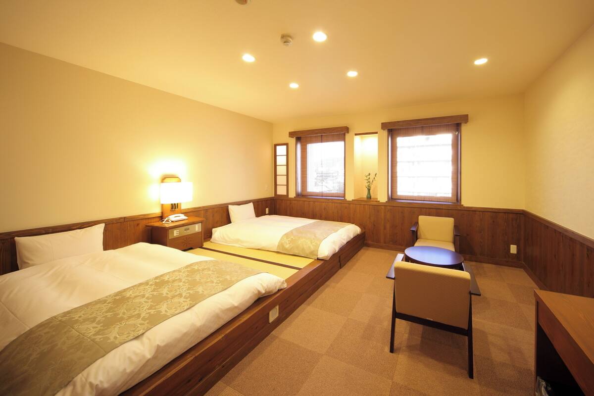 A hotel room with two beds, a desk, and a chair.