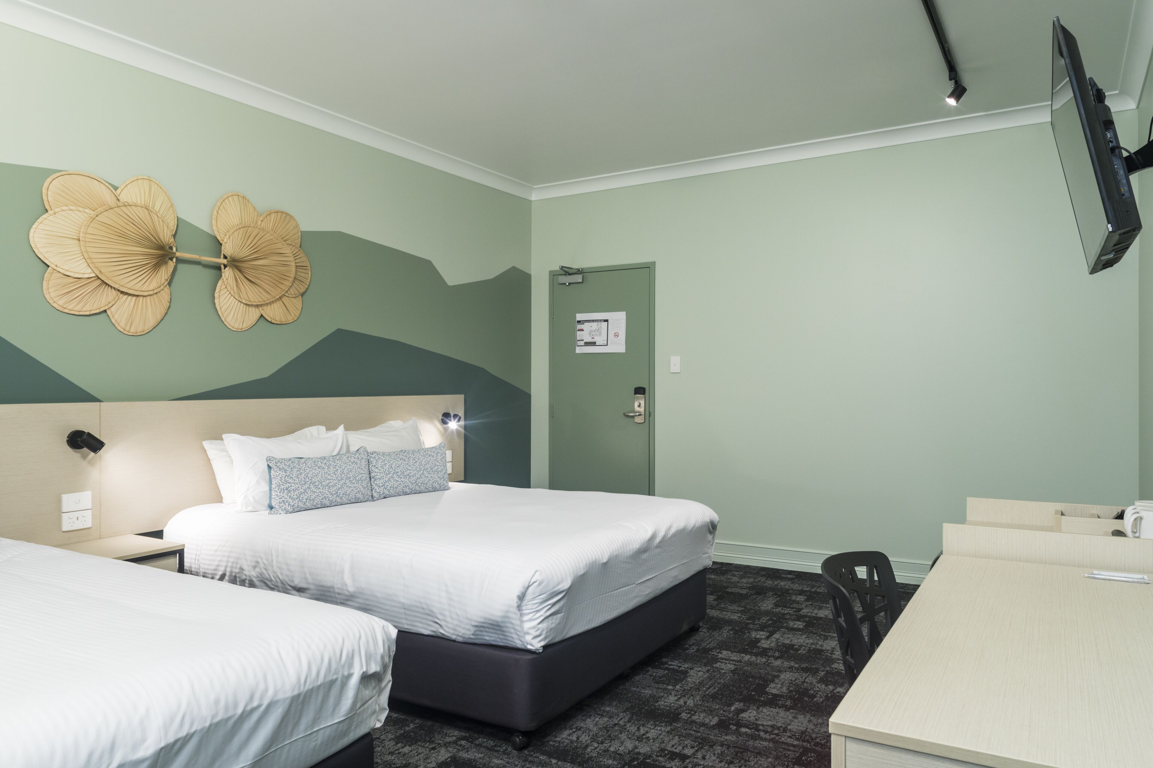 Habitación de hotel con dos camas, un escritorio, un televisor de pantalla plana y un adorno en la pared.