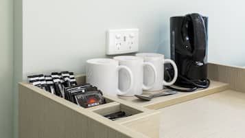 Una estación de café con cafetera, tazas y cápsulas de café.