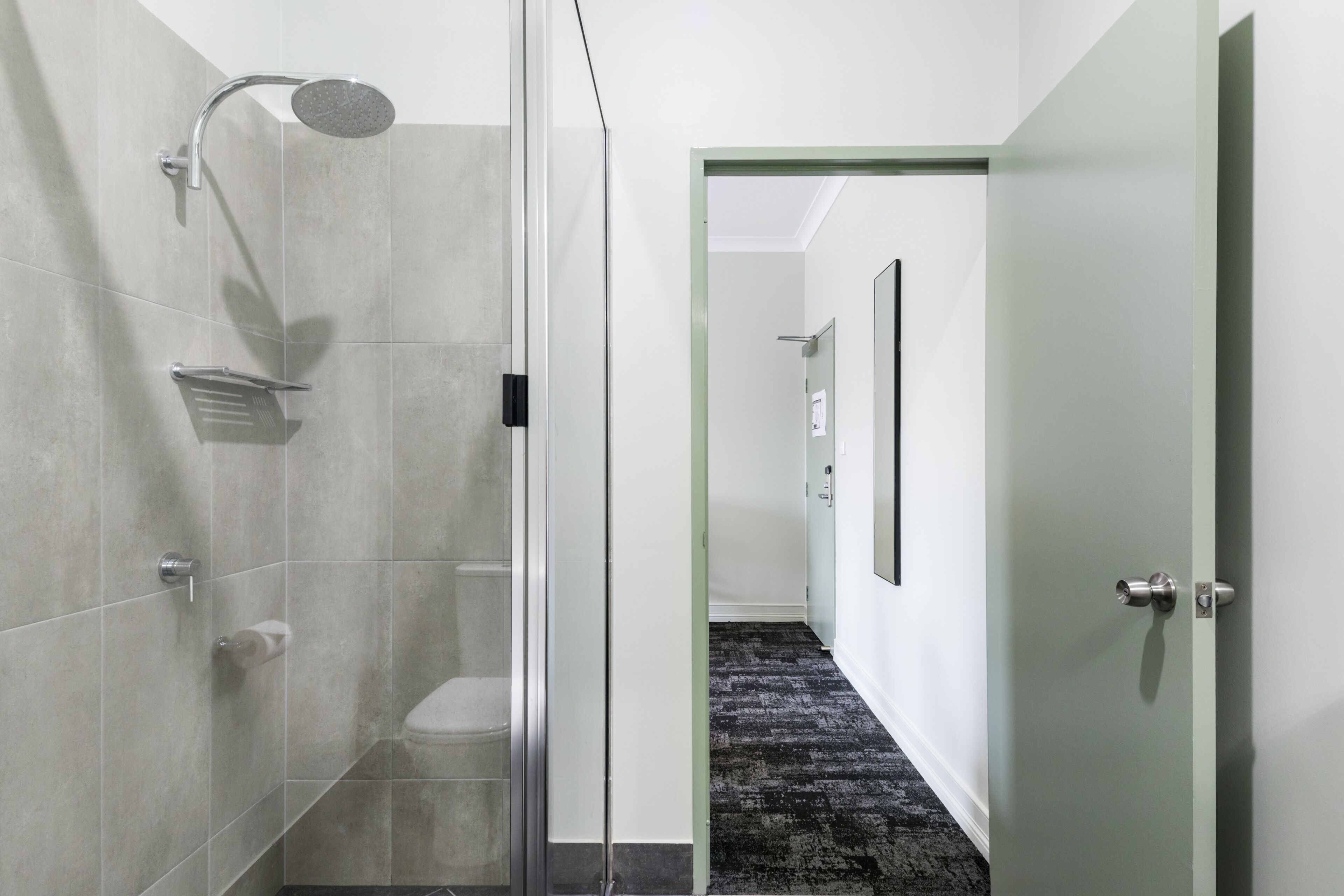 Une salle de bain moderne dotée d’une cabine de douche en verre, de toilettes et d’une douche à l’italienne.