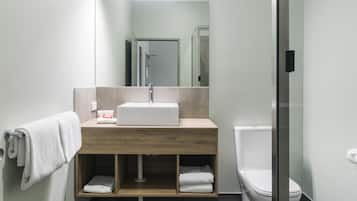 Une salle de bain moderne avec un meuble-lavabo en bois, un lavabo blanc et une cabine de douche en verre.