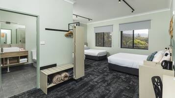 A modern hotel room with a bathroom, a bed, a desk, and a wardrobe.