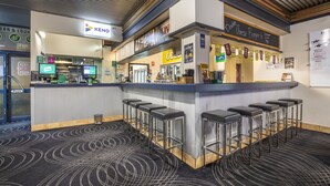 Uma área de bar com balcão, banquetas e uma placa com a inscrição 'Keno'.