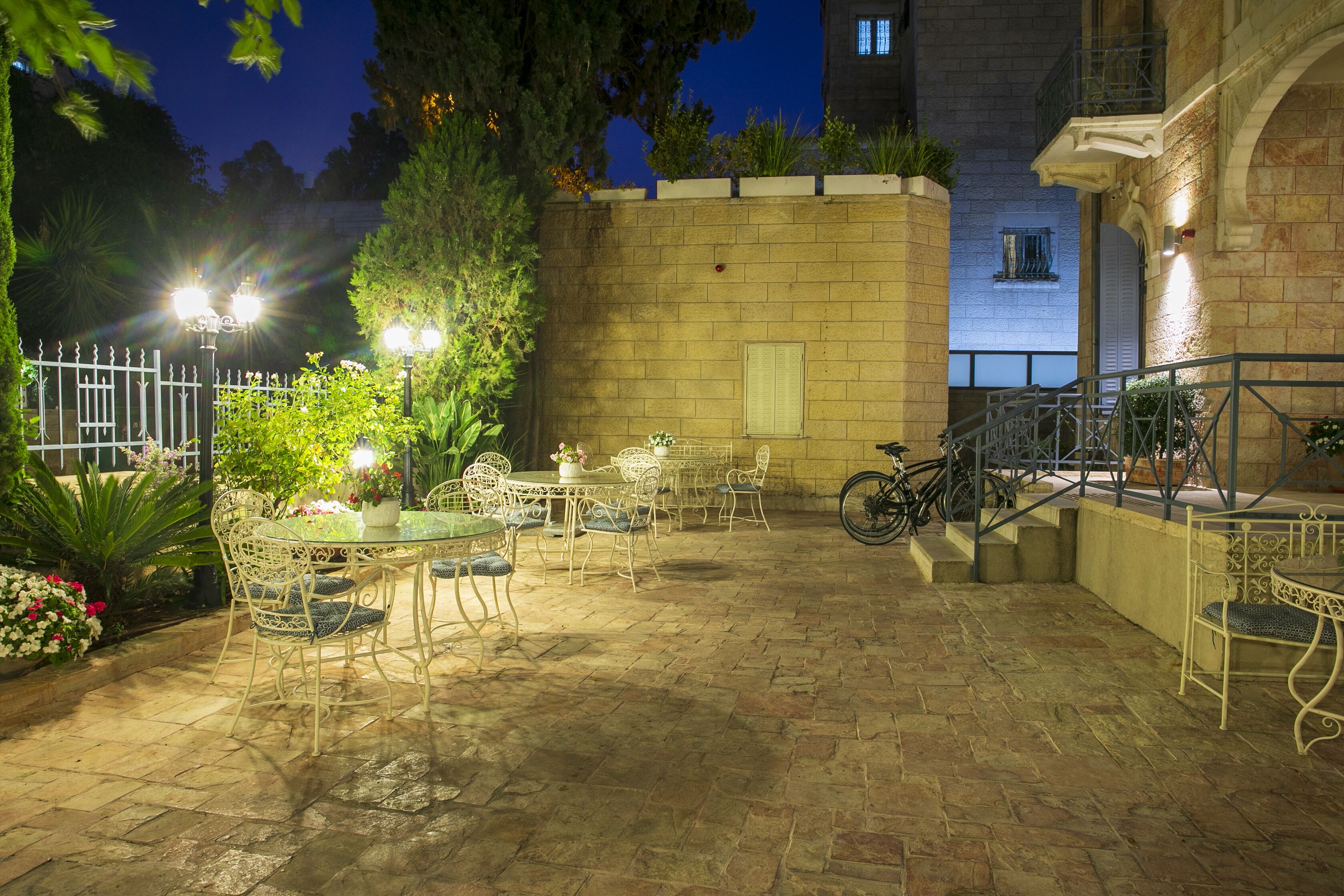 An outdoor patio with tables and chairs, a bicycle, and a brick wall.