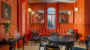 Une pièce avec une table ronde, des chaises, un canapé et une grande fenêtre avec des rideaux.
