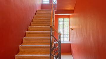 Una escalera de madera con barandales de metal que conduce a un rellano con una ventana.