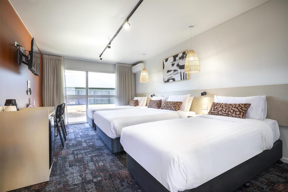 Ein Hotelzimmer mit zwei Betten, einem Schreibtisch und Blick ins Freie.