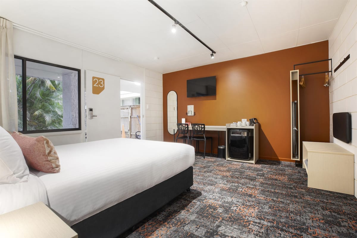 Ein Hotelzimmer mit Bett, Schreibtisch, Fernseher und Duschbereich.