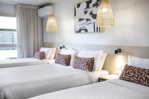 A hotel room with two beds, a large window with curtains, a wall-mounted air conditioner, and a large abstract painting. - Nightcap at Dalrymple Hotel (Garbutt)