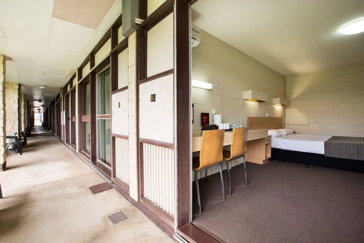 Ein Hotelzimmer mit Bett, Schreibtisch, Stühlen und einer Küchenzeile.