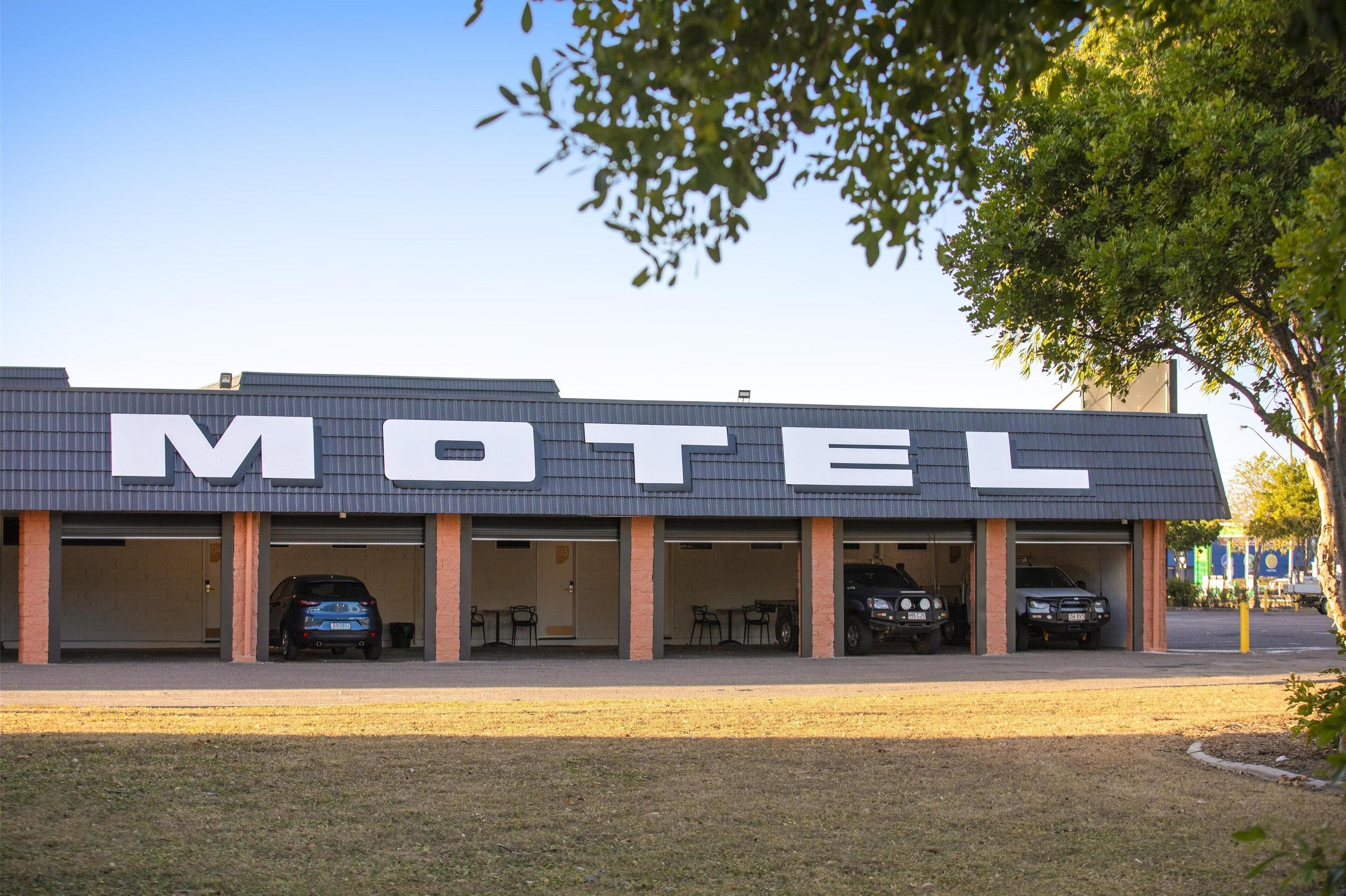 A motel with a large sign reading "MOTEL" and multiple parking spaces in front.