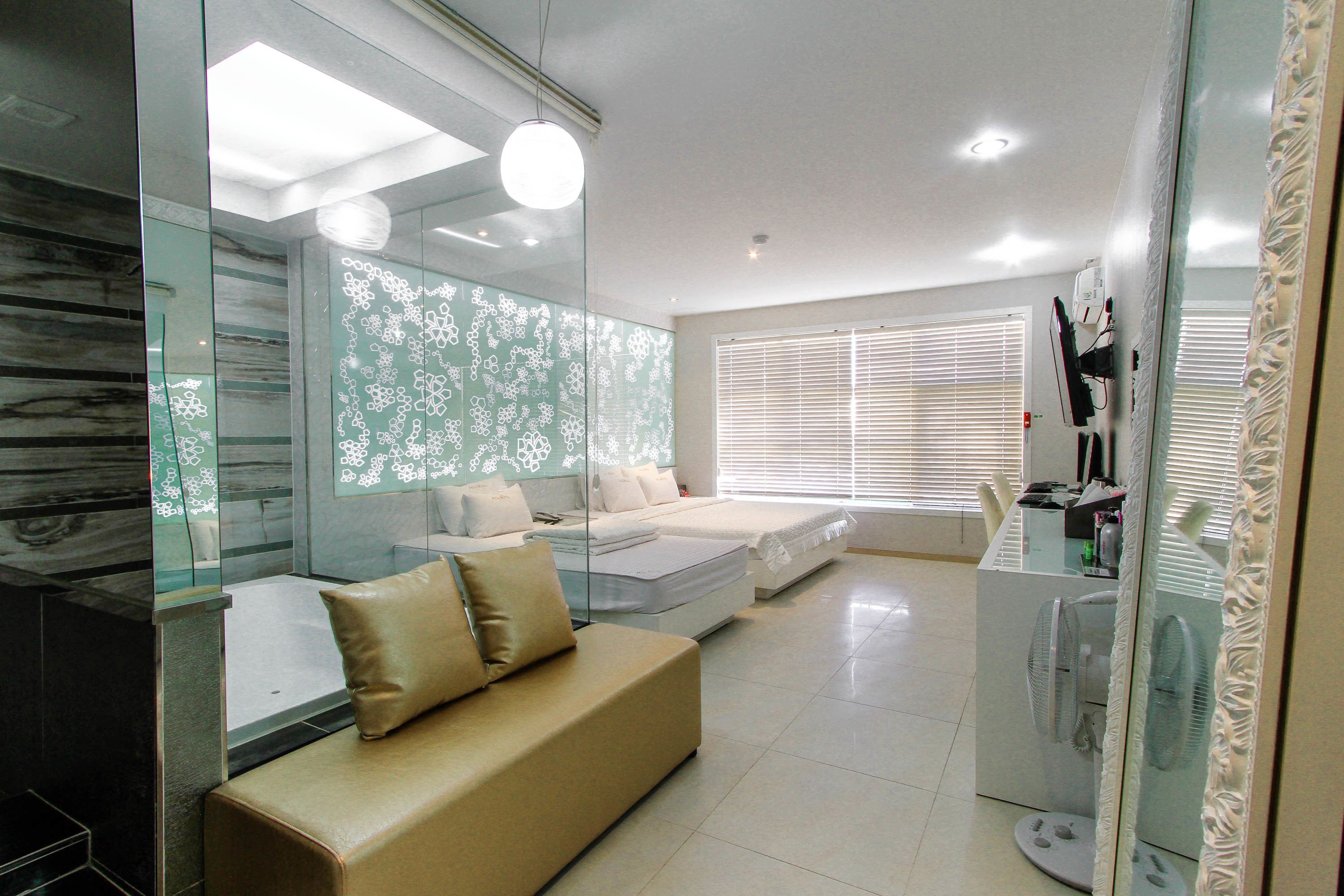 A modern living room with a sofa, a glass partition, and a fan.
