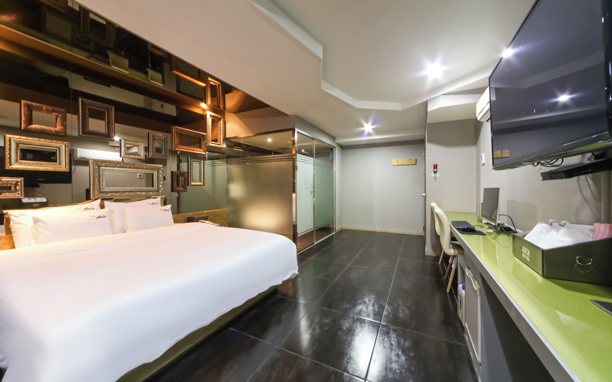 Una habitación de hotel con cama, escritorio con computadora, televisor y armario.