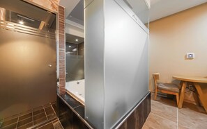 A modern bathroom with a glass shower enclosure, a wooden bench, and a small table. - Hotel Aria Nampo (Busan)