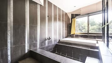 A modern bathroom with a large bathtub, a shower area, and a window with curtains.
