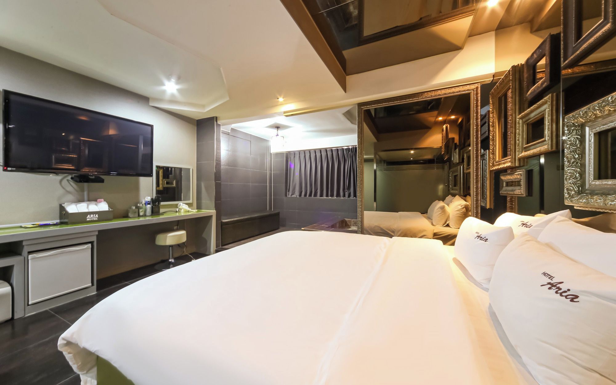 Une chambre d’hôtel avec un grand lit, un téléviseur à écran plat, un bureau avec un téléphone et un miroir.