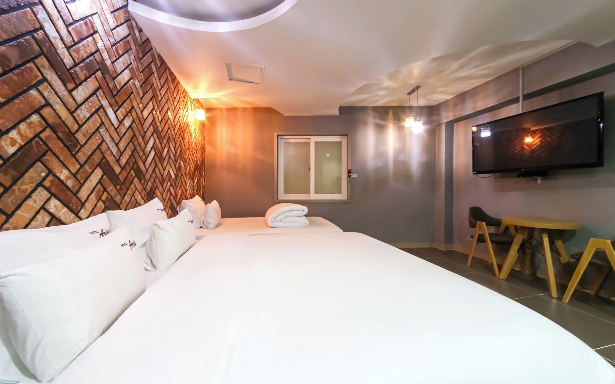 Habitación de hotel con una cama grande, un televisor de pantalla plana montado en la pared y un revestimiento de madera decorativo.
