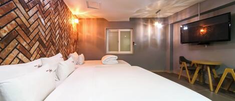 Habitación de hotel con una cama grande, un televisor de pantalla plana montado en la pared y un revestimiento de madera decorativo.