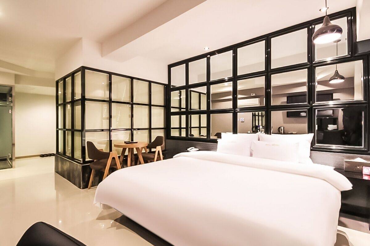 A modern hotel room with a large bed, a desk, and a seating area.