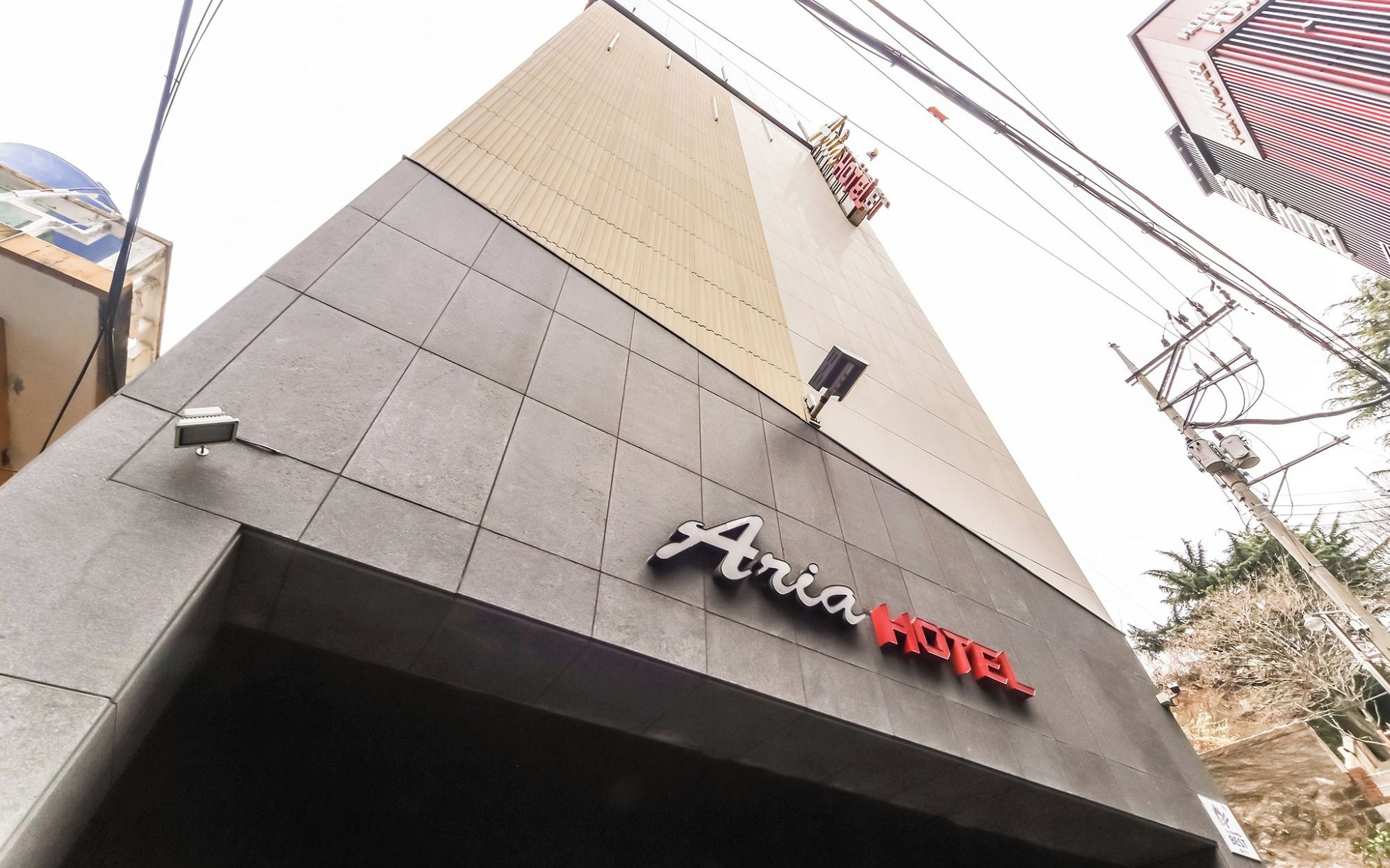 Exterior del Hotel Aria, con un diseño moderno, destacando un letrero llamativo y una cámara de seguridad.