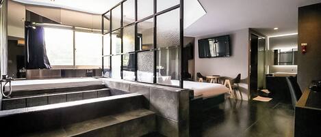 A modern hotel room with a large window, a staircase, a bed, a desk, and a bathroom.
