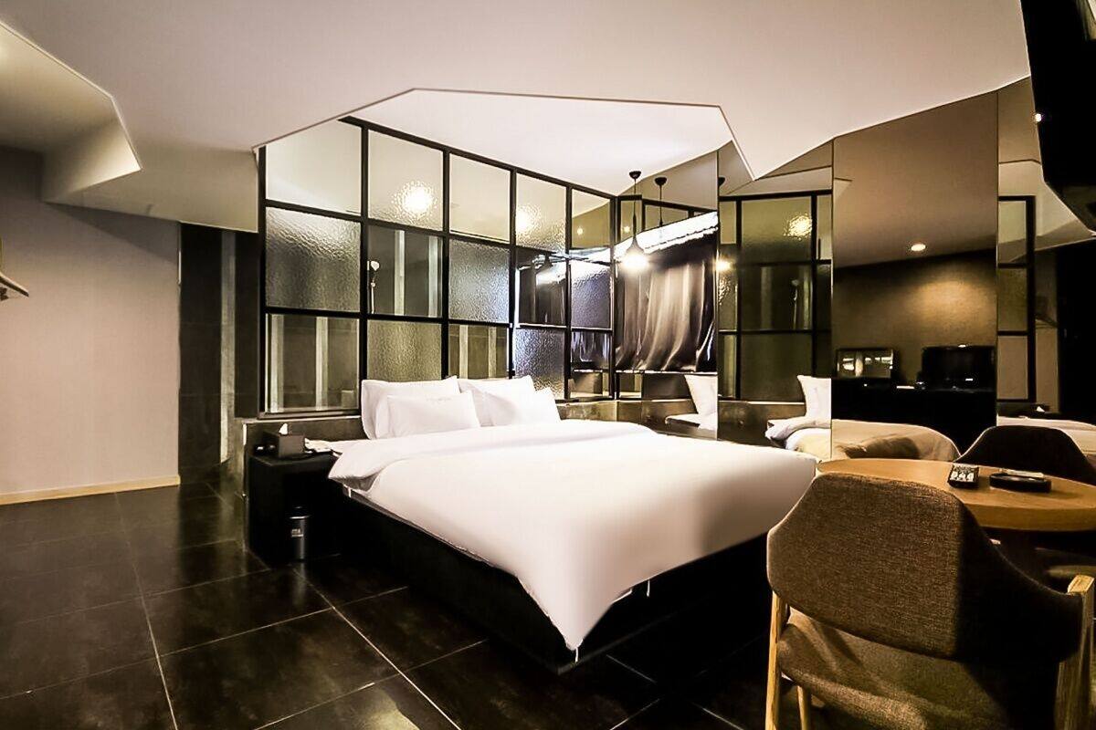 A modern hotel room with a large bed, a desk, and a chair.