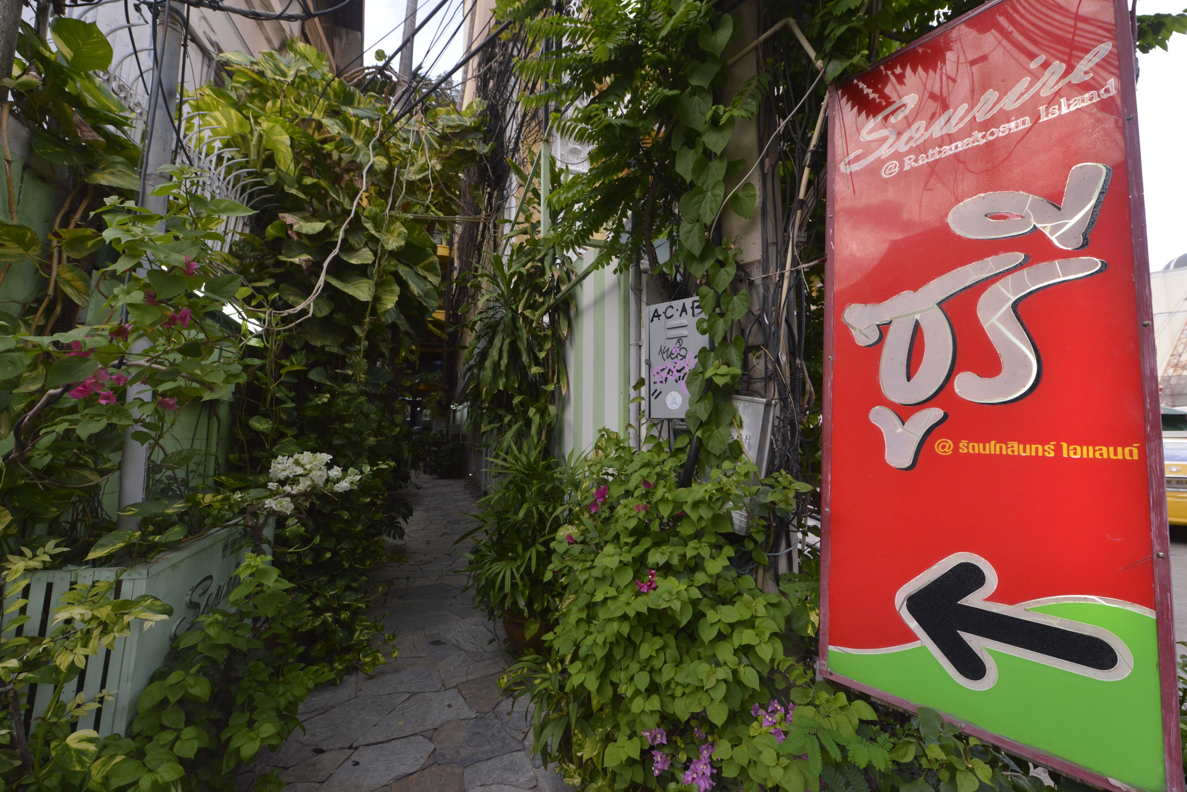 A narrow alley with a red sign indicating a direction.
