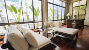 A spacious room with large windows, a wooden floor, a sofa, a small table, and a desk. - Sourire at Rattanakosin Island (Bangkok)