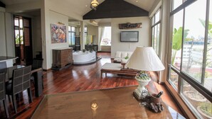 A spacious living area with a wooden floor, a large dining table, a sofa, and a TV mounted on the wall. - Sourire at Rattanakosin Island (Bangkok)