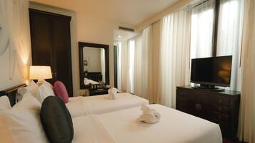 A hotel room with two beds, a television, a dresser, and a mirror.