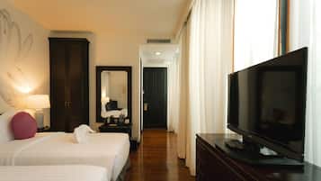 Habitación de hotel con dos camas, televisión, cómoda y un pasillo que conduce a una puerta.