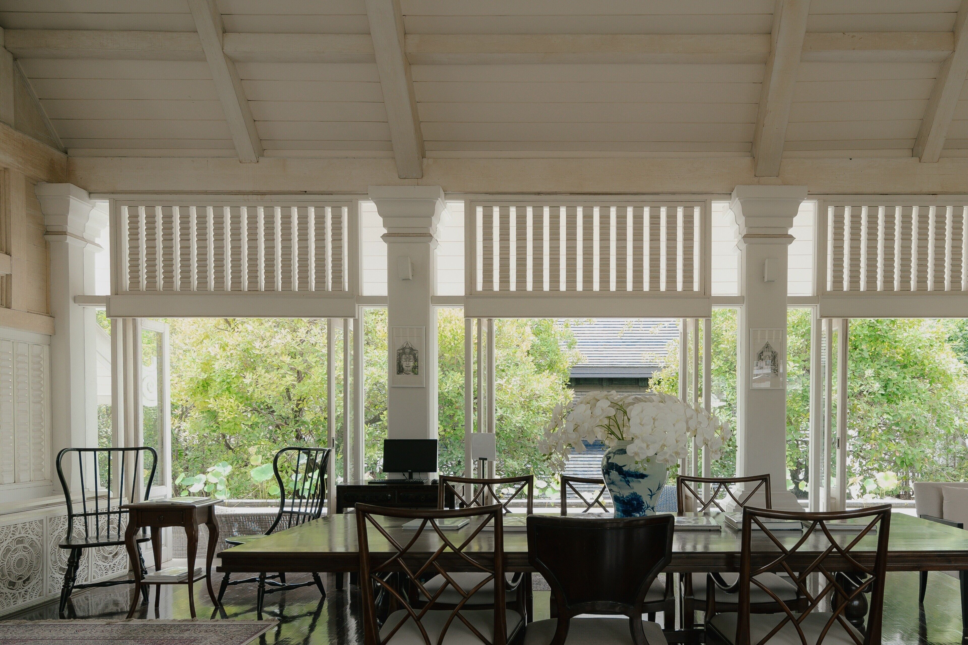 A dining area with a table, chairs, and a vase of flowers.