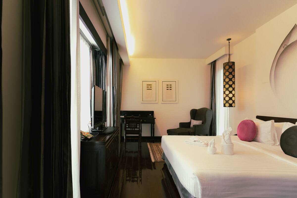 A hotel room with a bed, a desk, a chair, and a large window.