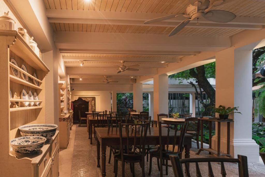 A restaurant with wooden furniture, white columns, and ceiling fans.