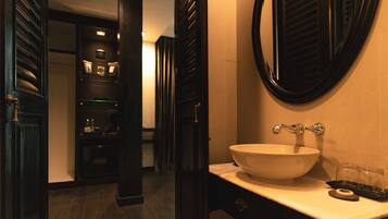 Un baño con un espejo ovalado grande, un lavabo blanco y un mueble de tocador de madera oscura.