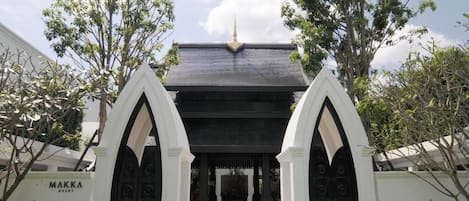A building entrance with a dark roof and a golden spire.