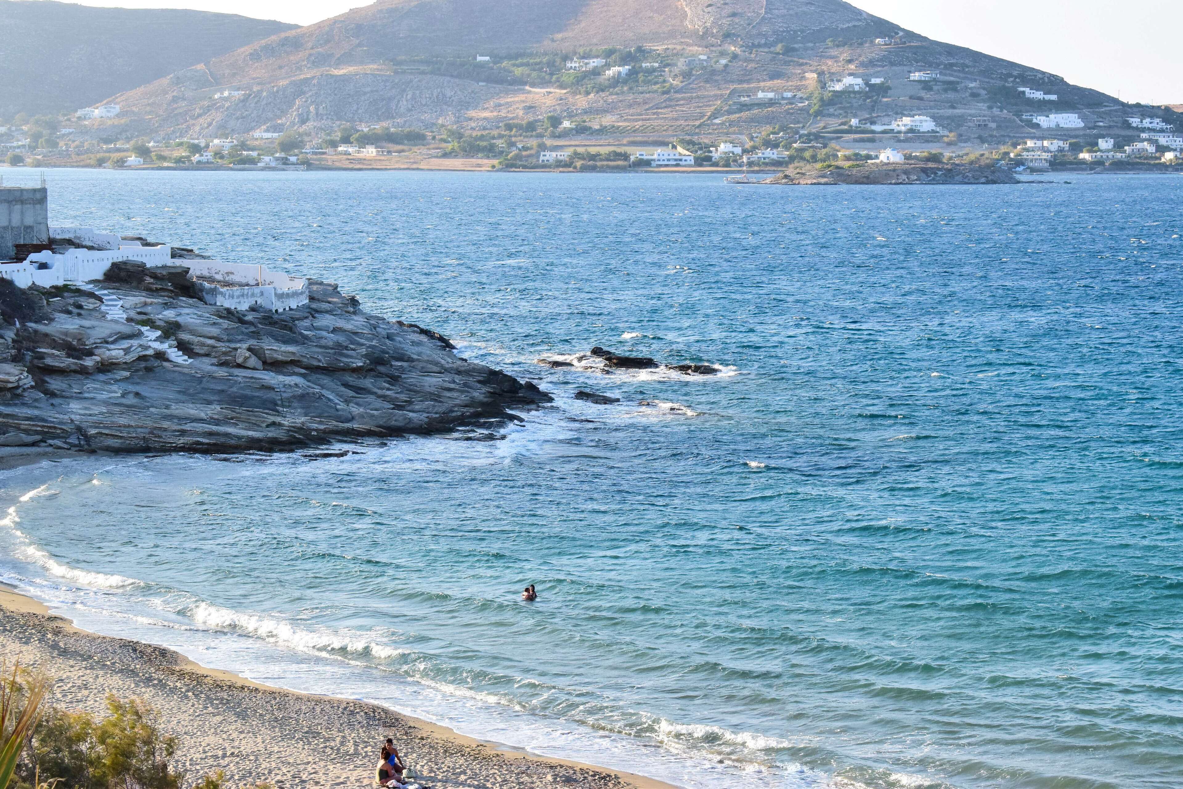 A coastal view with rocky terrain, a beach, and a distant village.