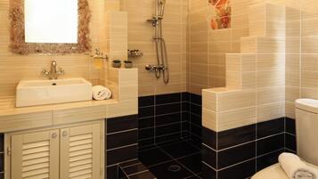Une salle de bain moderne équipée d’un lavabo, d’un miroir, d’une douche et de toilettes.