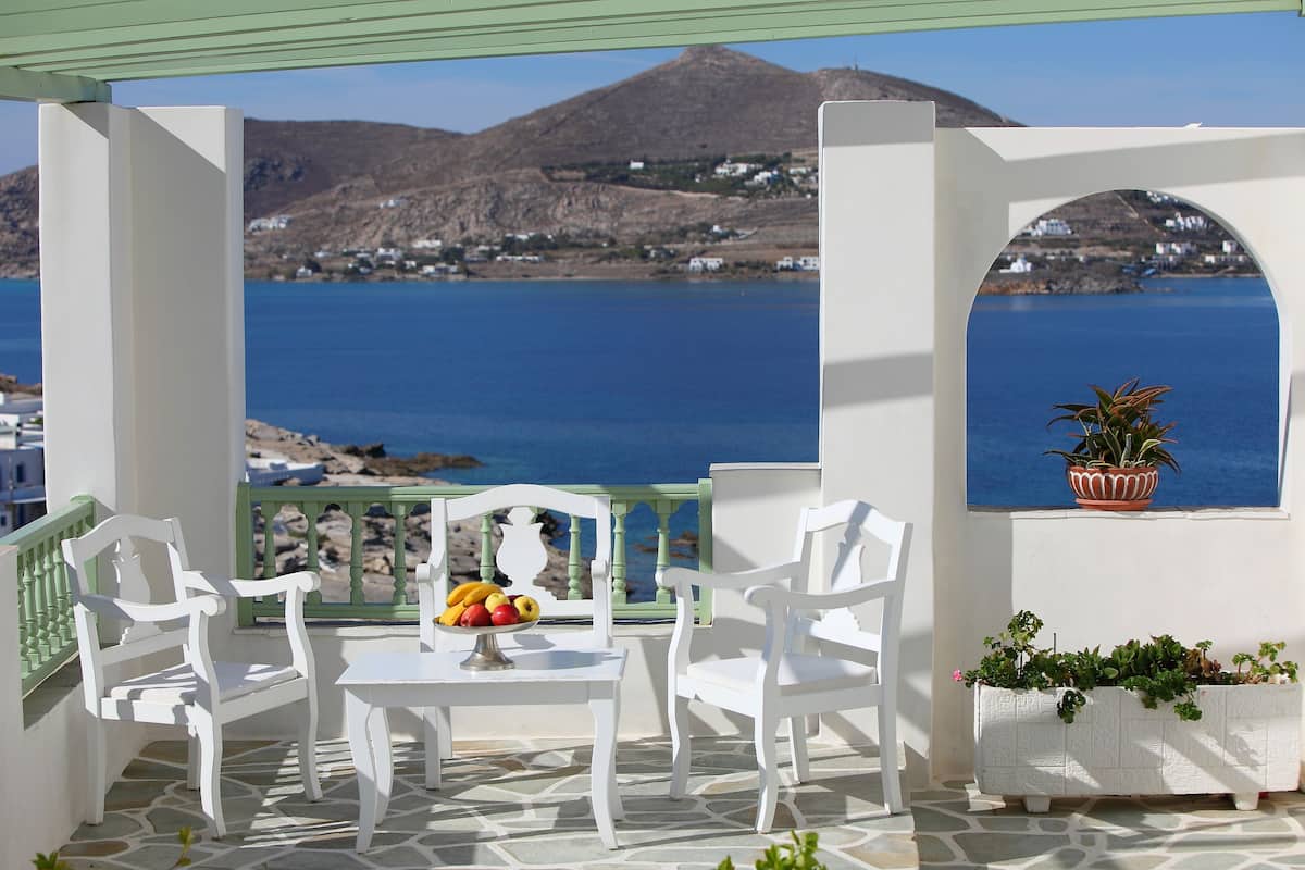A terrace with white furniture, a table with fruit, and a potted plant.