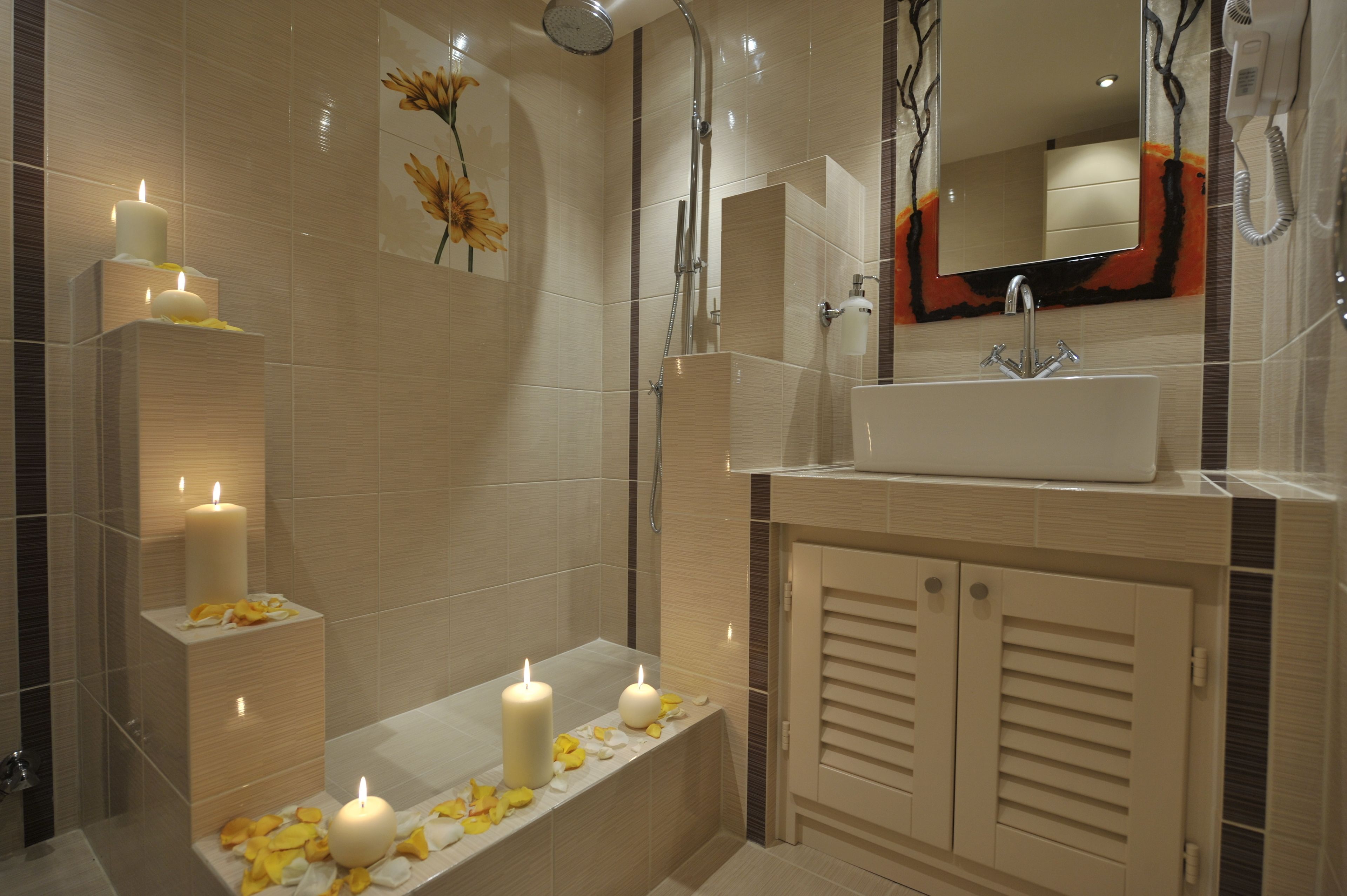 Un baño moderno con bañera, lavabo y ducha. Hay velas y pétalos de flores sobre la bañera.
