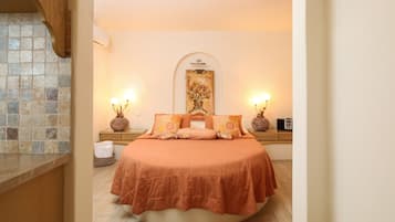 Un dormitorio con una cama redonda, dos mesitas de noche con lámparas, un cuadro colgado en la pared y un salpicadero de azulejos.