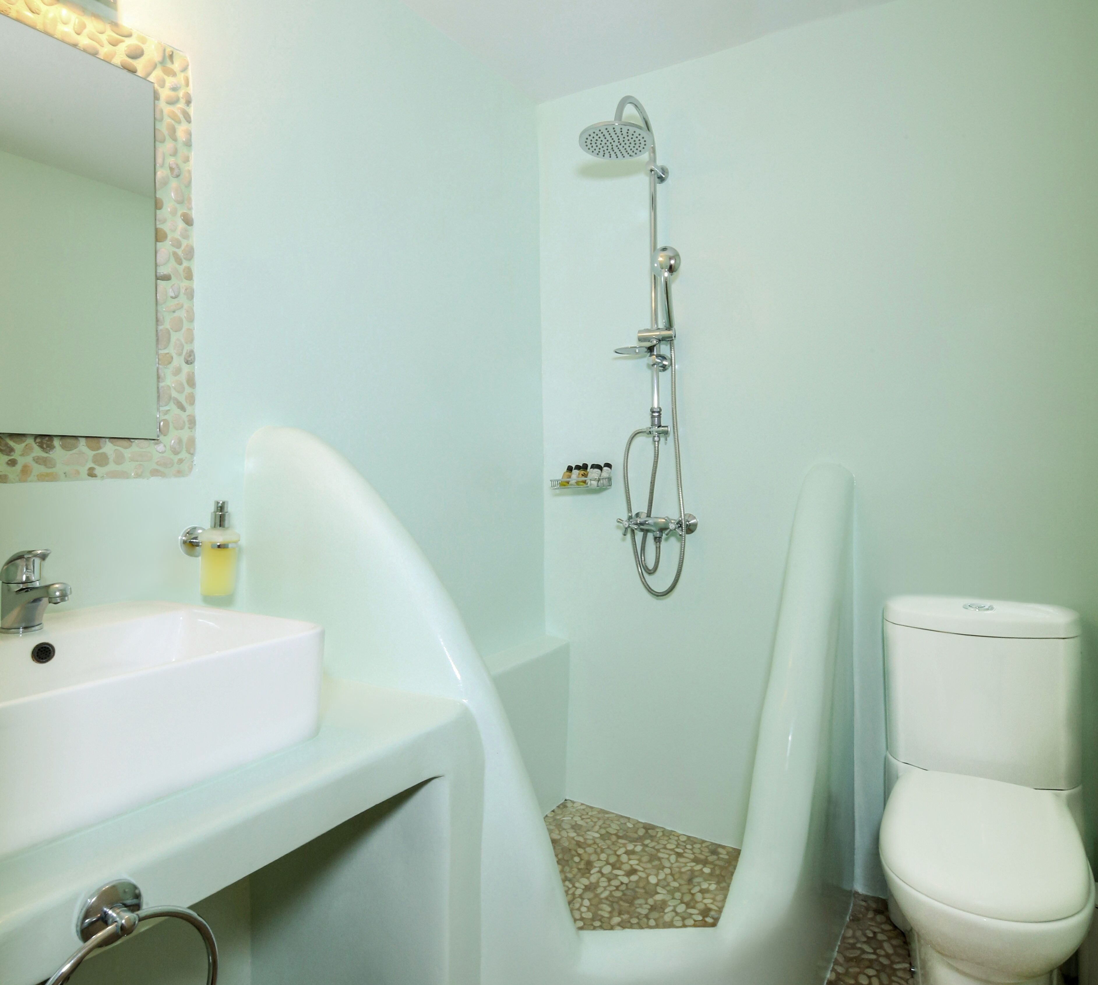 Un baño con un lavamanos blanco, un inodoro y una ducha con cabezal de ducha manual.