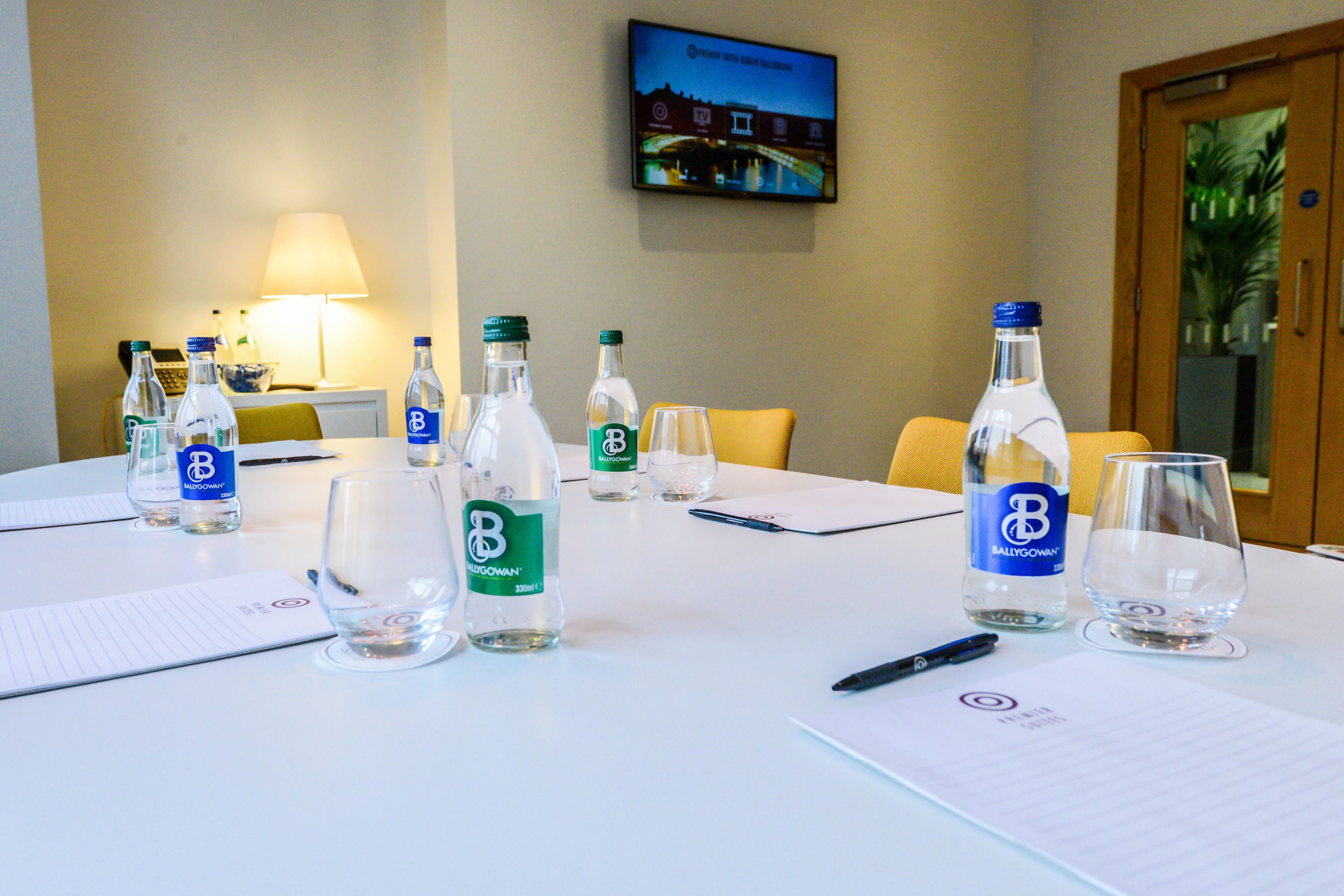 A conference table with water bottles, glasses, and notepads, indicating a meeting setup.