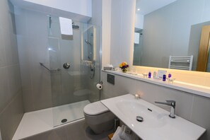 A modern bathroom with a glass-enclosed shower, a white sink, and a large mirror. - Premier Suites Dublin Ballsbridge (Dublin)