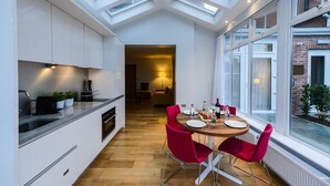 Una cocina moderna con tragaluces, un comedor con sillas rojas y vistas a un edificio de ladrillo.