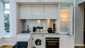 Una cocina compacta equipada con lavadora, horno y refrigerador.